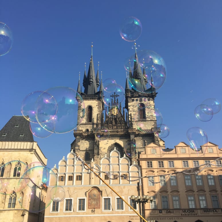 Bubbles floating in front of a building in Prague.